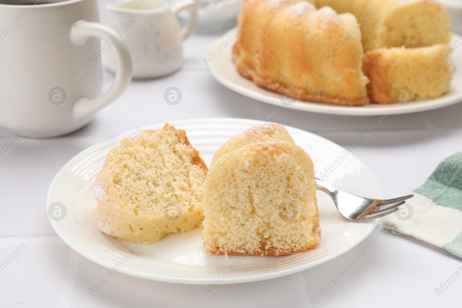 Photo of Pieces of delicious sponge cake and fork on white table, closeup