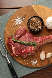 Photo of Raw ribeye steak, spices and fork on table, flat lay