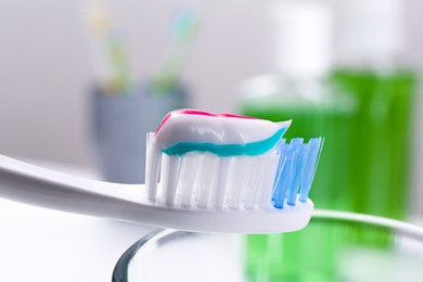 Photo of Toothbrush with paste near mouthwash on blurred background, closeup