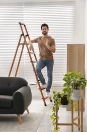 Photo of Man showing ok gesture on wooden ladder at home