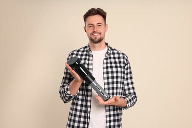 Photo of Smiling man holding sous vide cooker on beige background