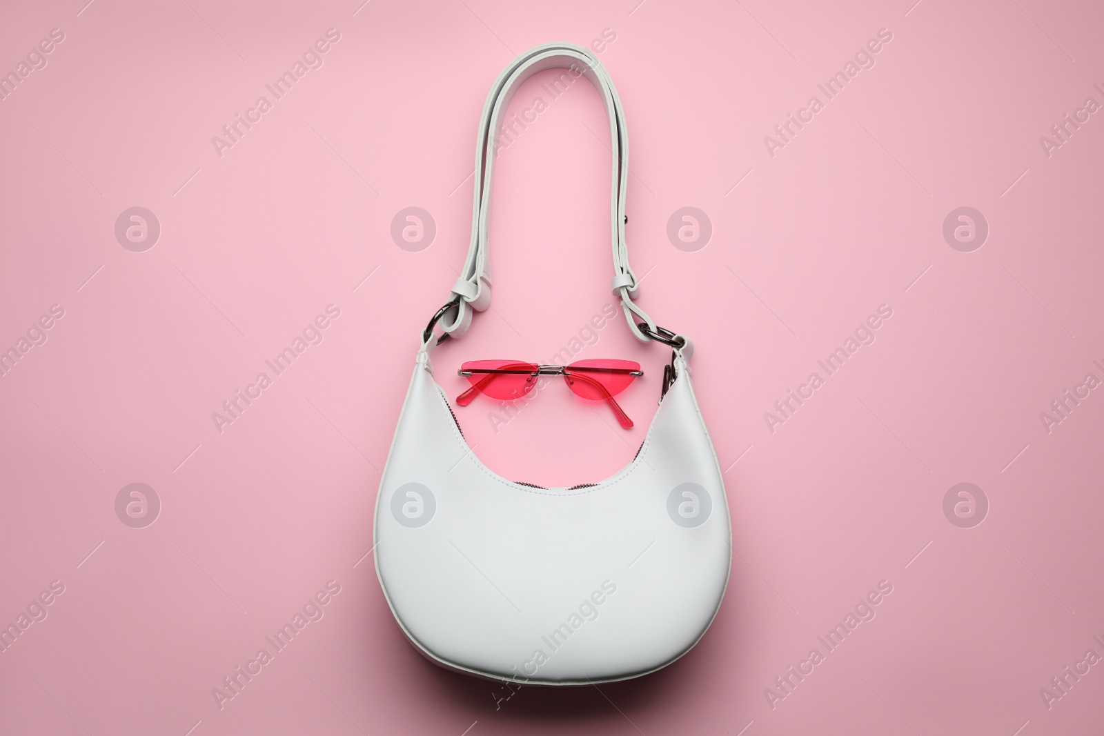 Photo of Stylish woman's bag and sunglasses on pink background, top view