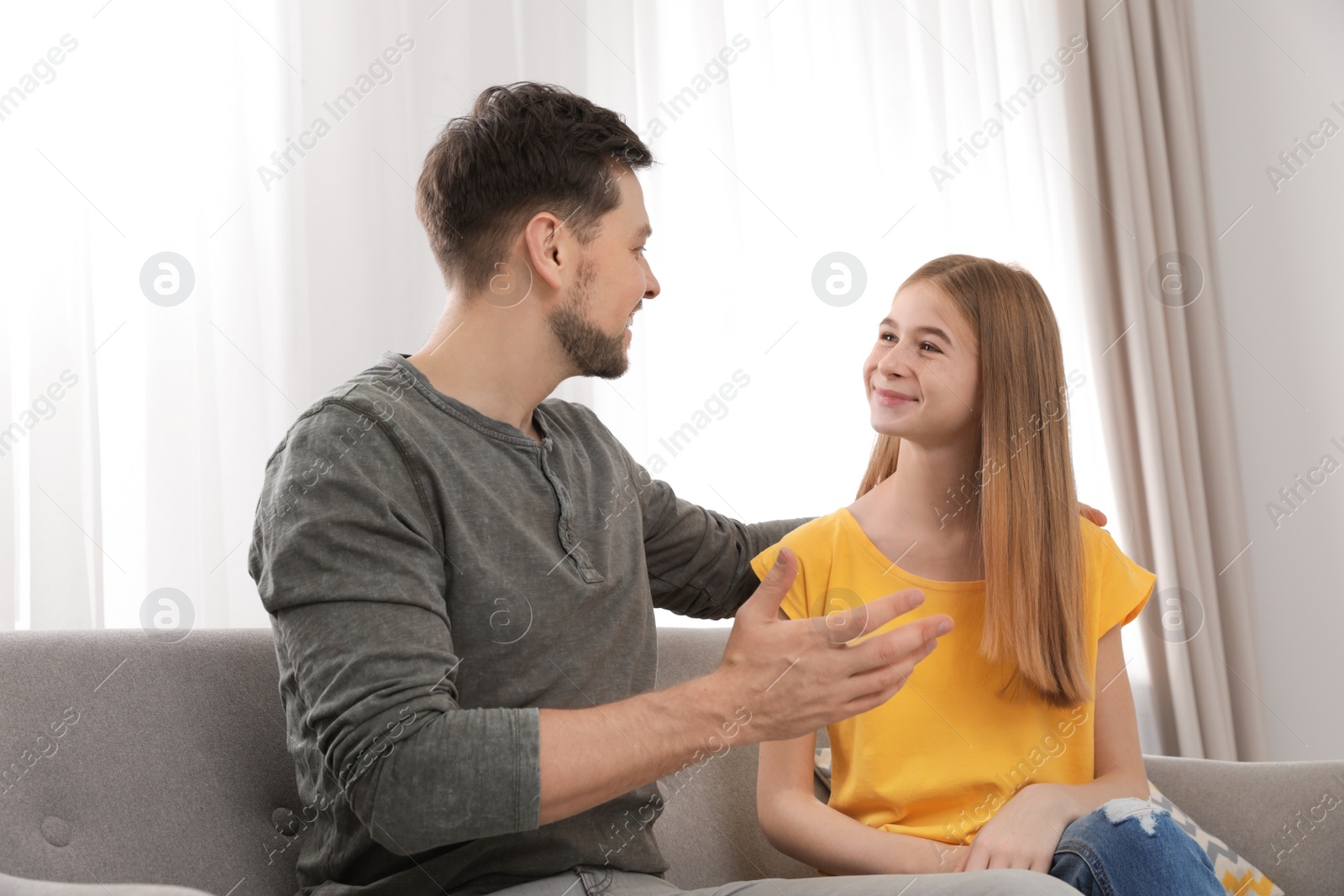 Photo of Father talking with his teenager daughter at home