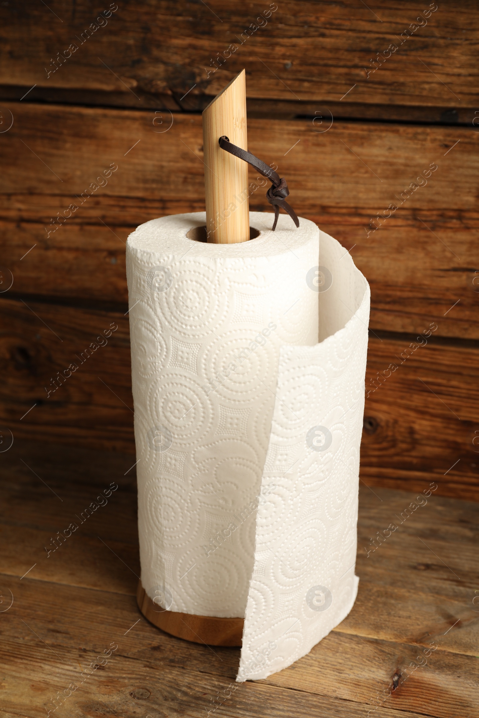 Photo of Holder with roll of white paper towels on wooden table