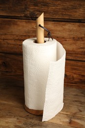 Holder with roll of white paper towels on wooden table