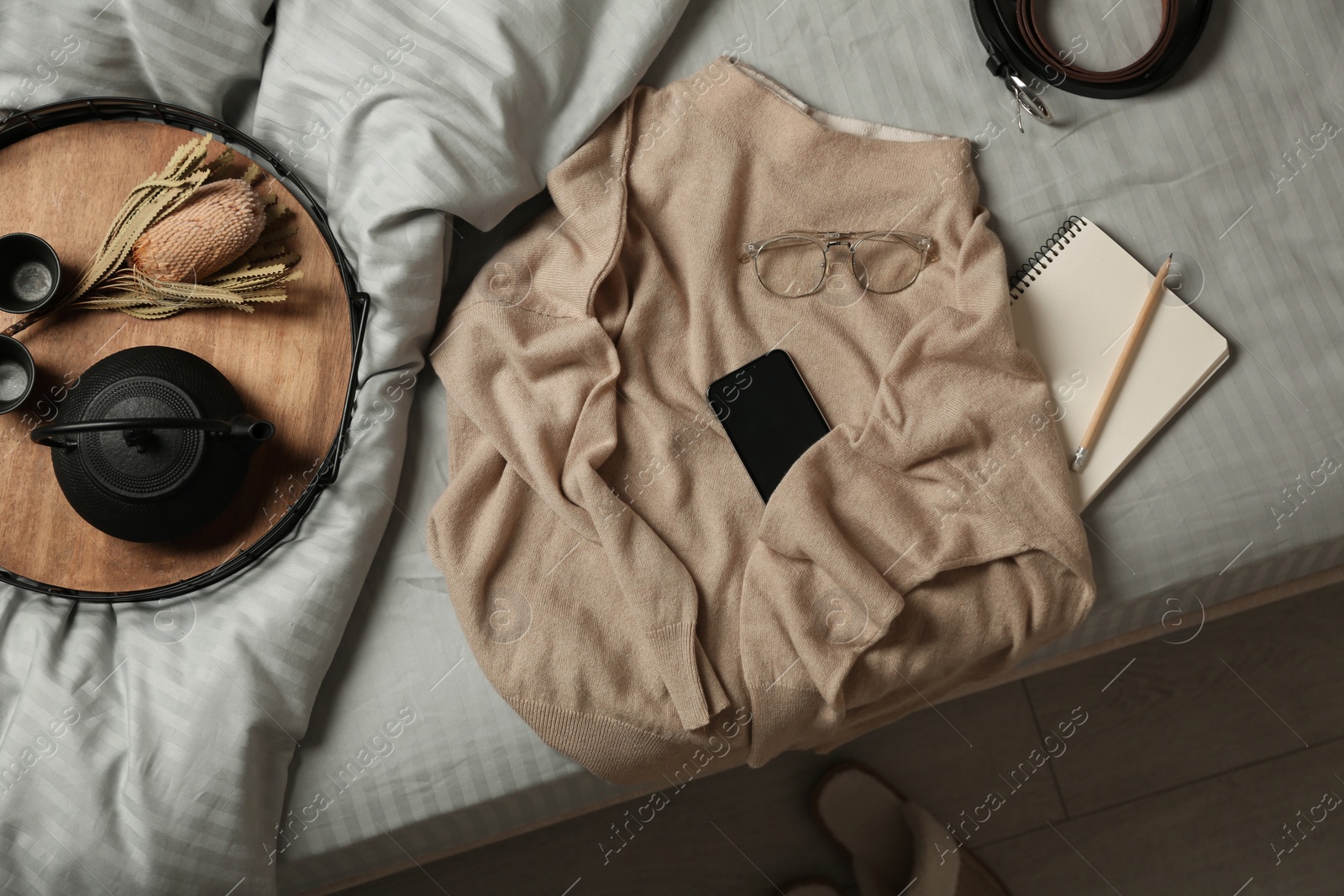 Photo of Soft cashmere sweater and tray with tea set on bed at home