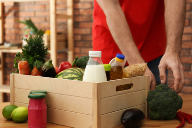 Man with fresh products at table indoors, closeup. Food delivery service