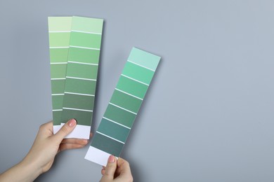 Photo of Woman with paint chips choosing color near grey wall, closeup. Interior design