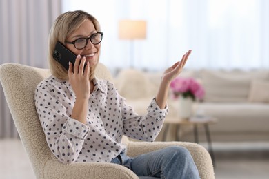 Photo of Happy woman talking on phone at home