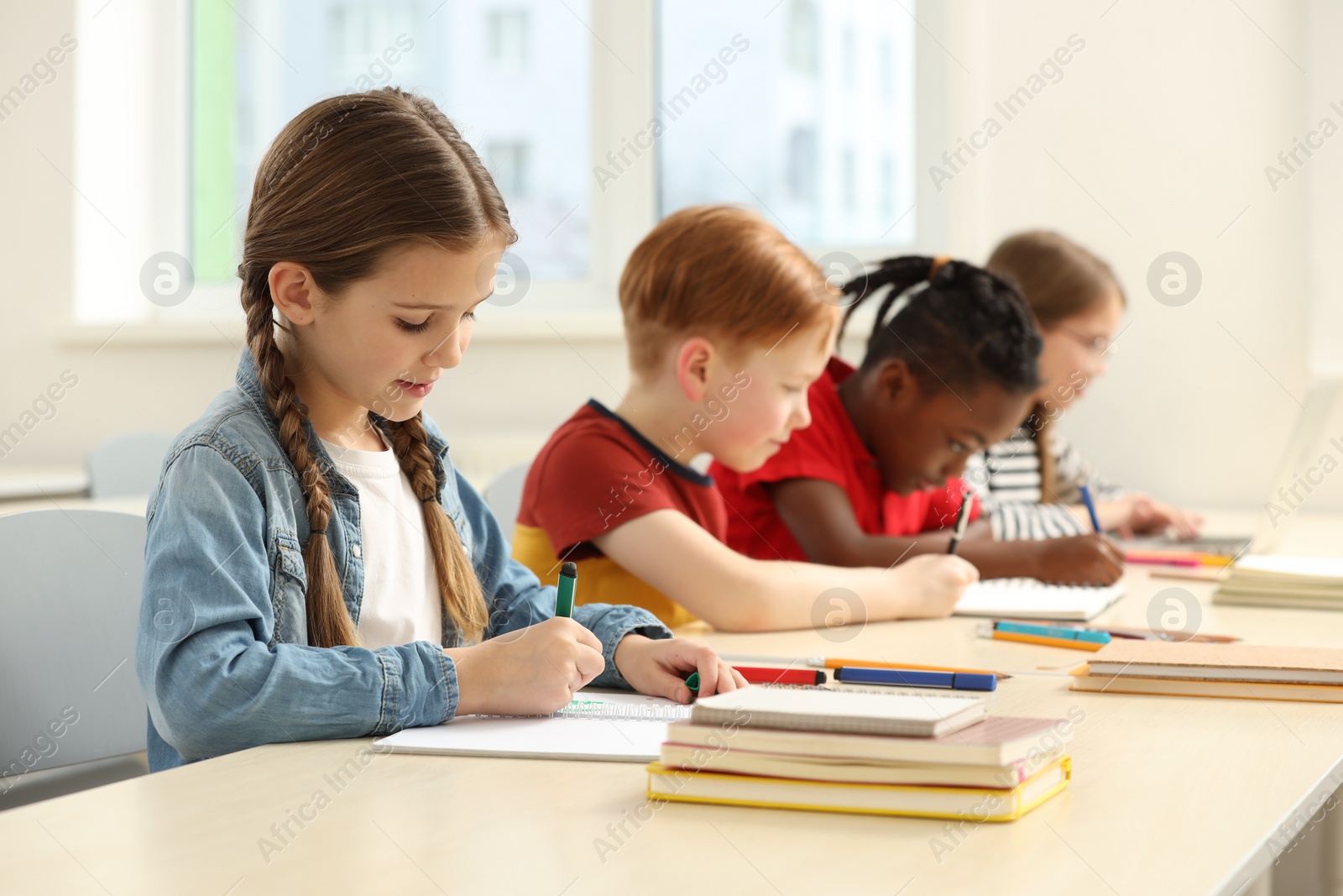 Photo of Cute children studying in classroom at school