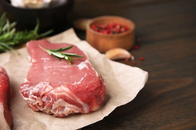 Fresh raw meat with rosemary on wooden table, closeup. Space for text