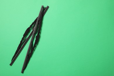 Car windshield wipers on green background, flat lay. Space for text