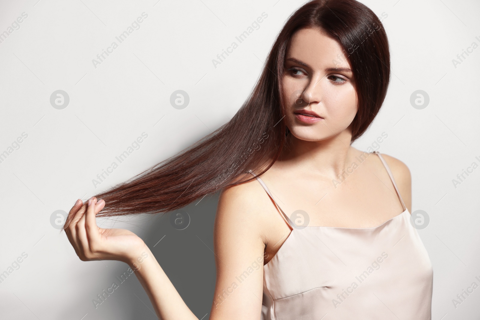 Photo of Portrait of beautiful young woman with healthy strong hair on light gray background