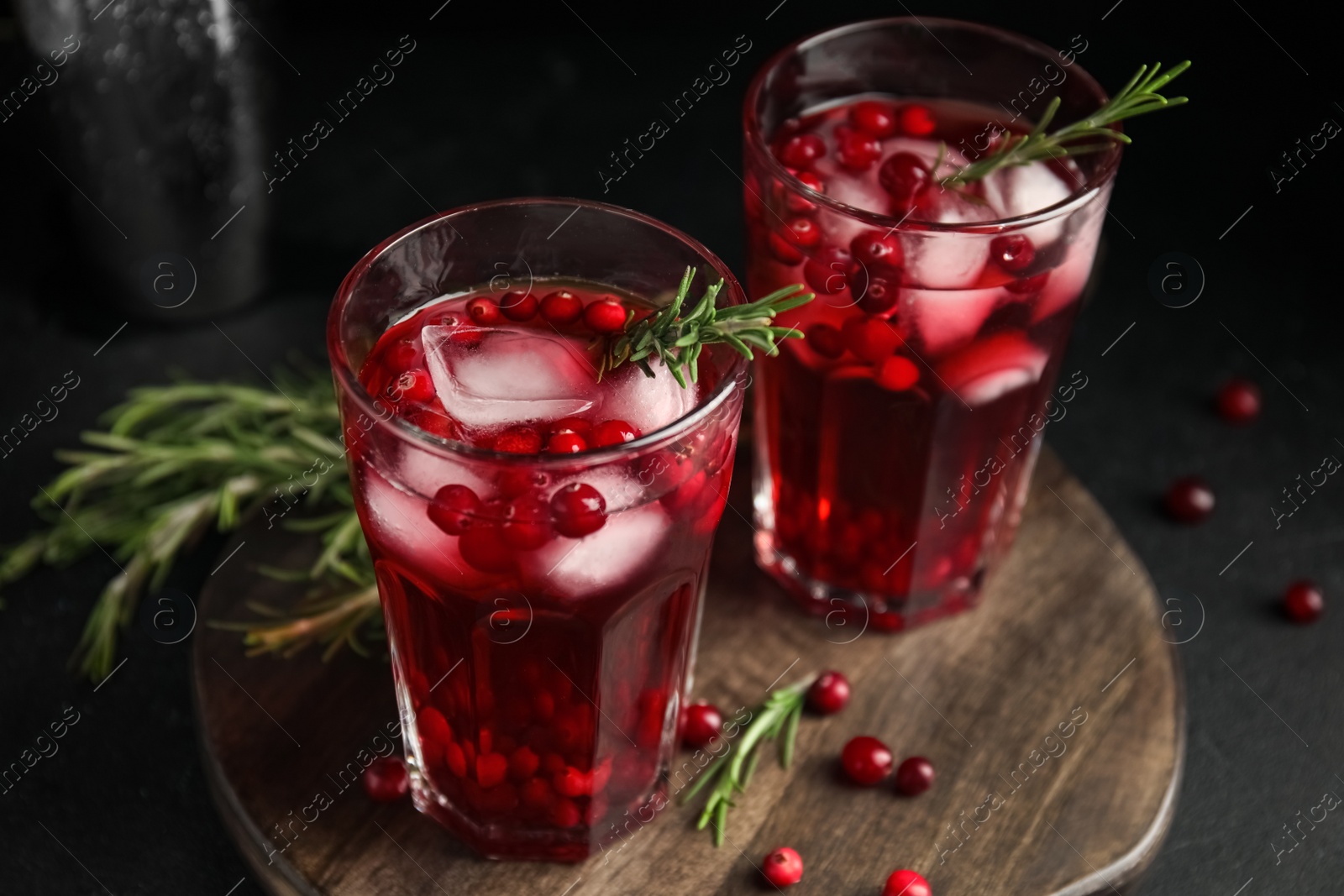 Photo of Tasty refreshing cranberry cocktail with rosemary on black table