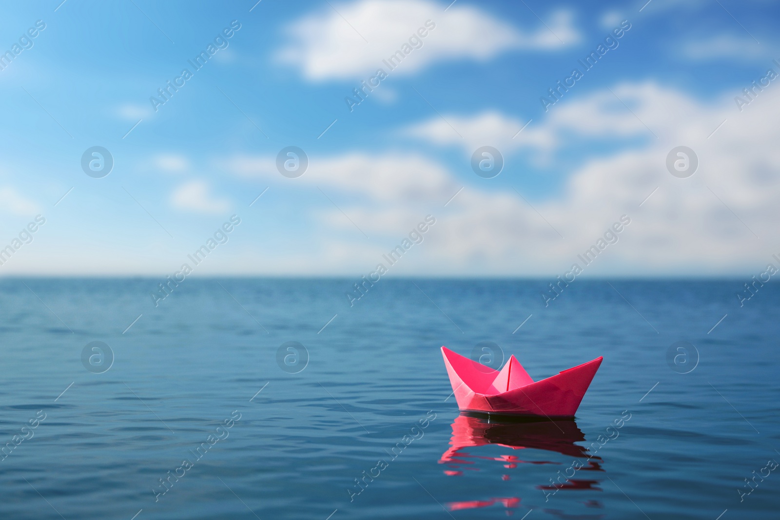 Image of Pink paper boat floating on calm sea. Space for text