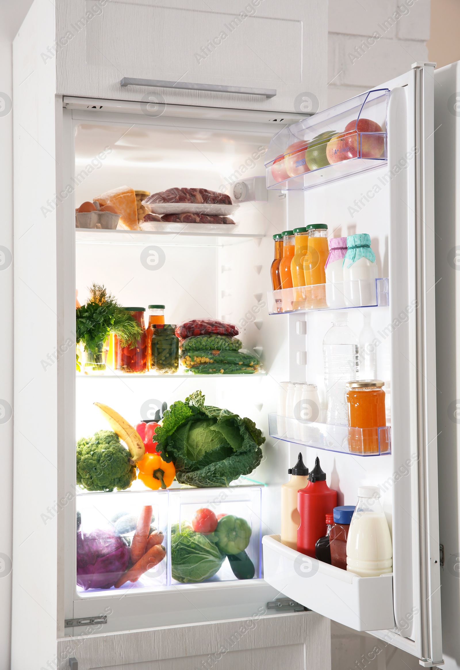 Photo of Modern refrigerator full of products in kitchen