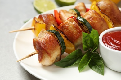 Delicious chicken shish kebabs with vegetables and ketchup on grey table, closeup