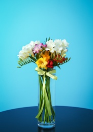 Photo of Glass vase with beautiful freesia on table against color background