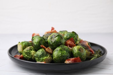 Photo of Delicious roasted Brussels sprouts, bacon and rosemary on white textured table, closeup