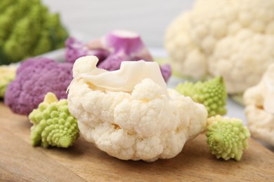 Photo of Various cauliflower cabbages on wooden board, closeup