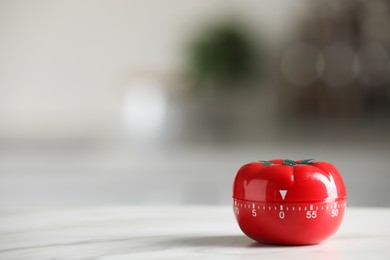 Photo of Kitchen timer in shape of tomato on white table against blurred background. Space for text