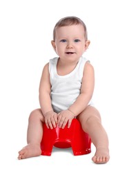 Little child sitting on baby potty against white background