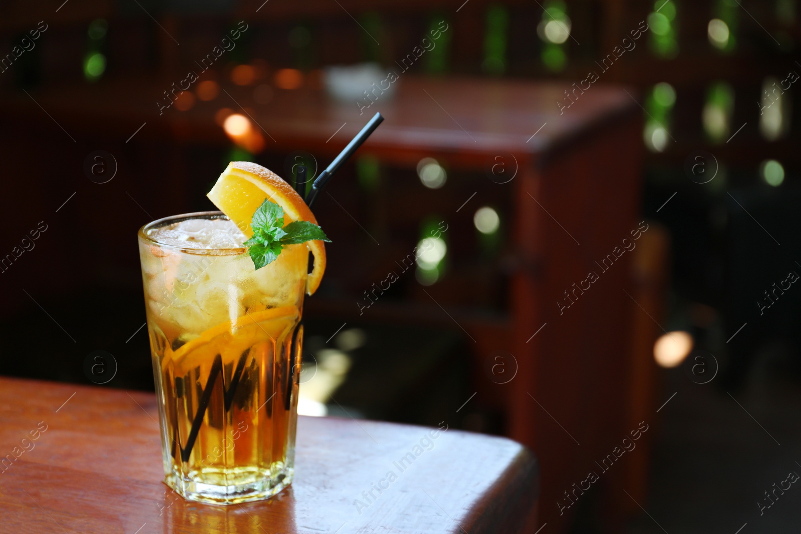 Photo of Glass of delicious cocktail with ice on table in bar