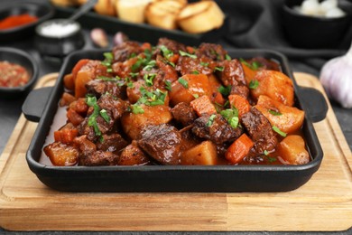 Delicious beef stew with carrots, parsley and potatoes on grey table, closeup