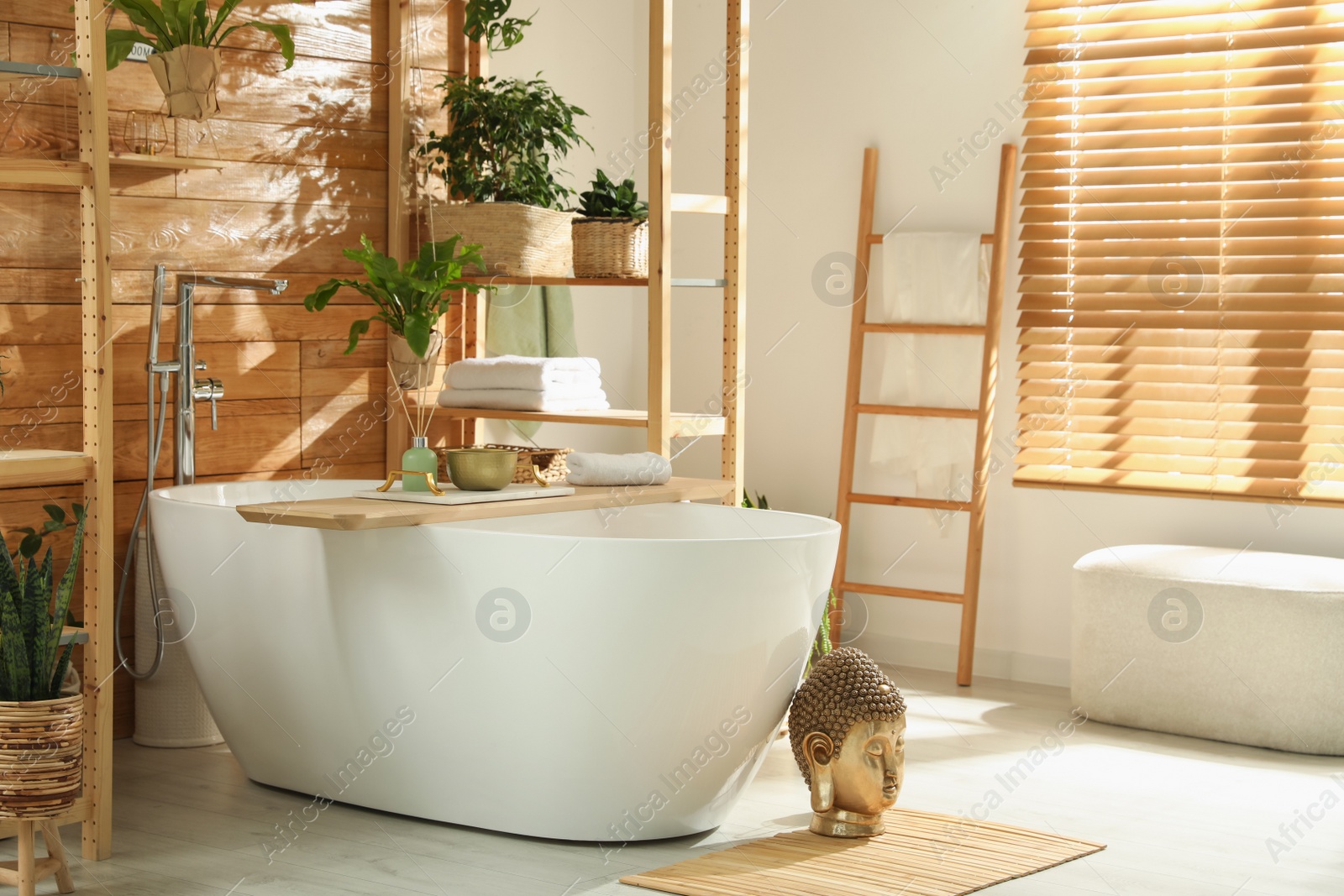 Photo of Stylish bathroom interior with white tub and green houseplants near wooden wall. Idea for design