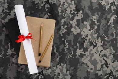 Books, pencils and diploma on camouflage background, top view with space for text. Military education concept