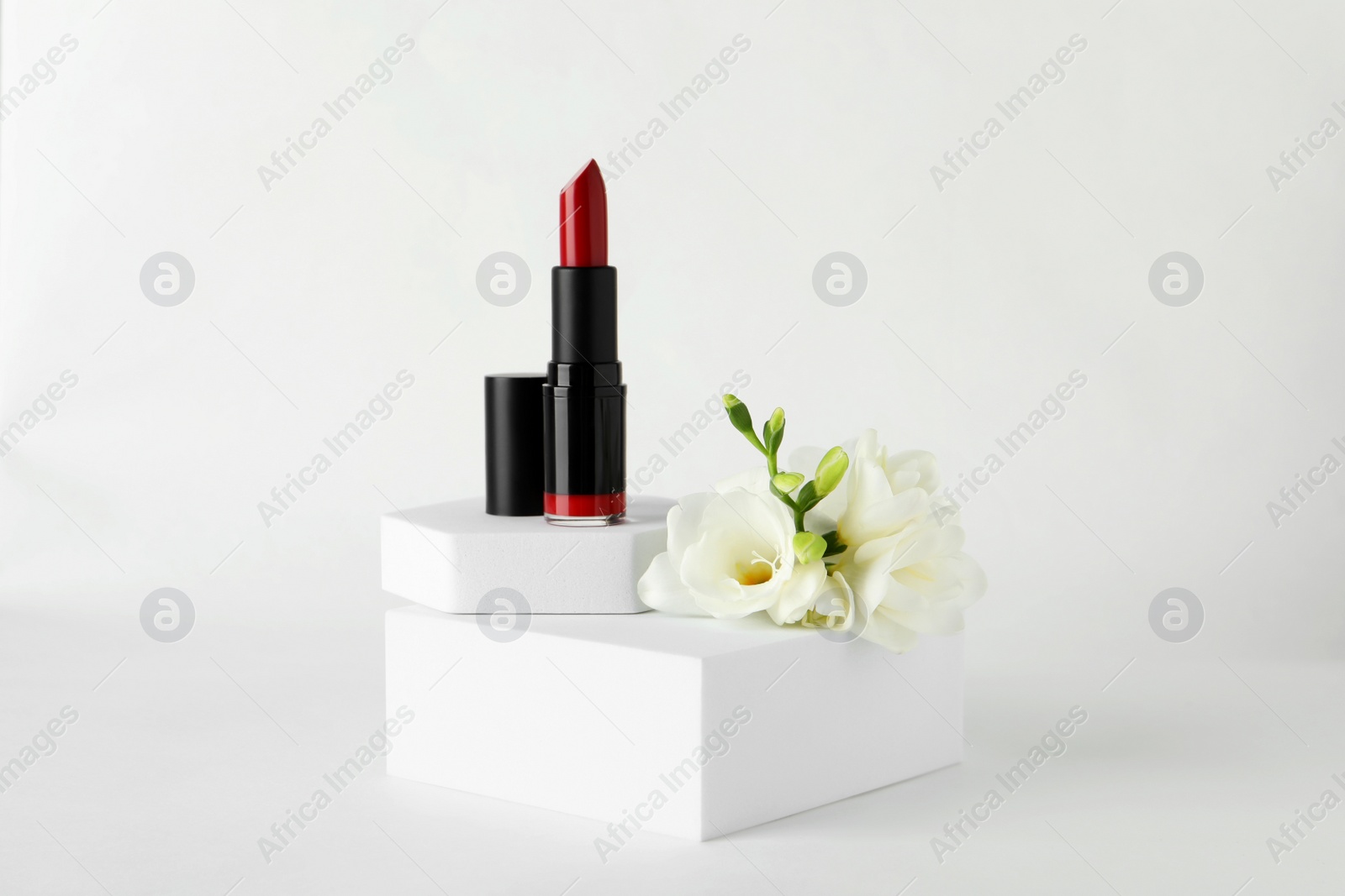 Photo of Beautiful red lipstick and eustoma flowers on white background