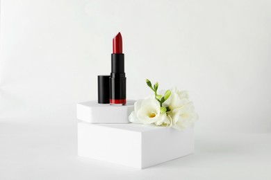 Beautiful red lipstick and eustoma flowers on white background