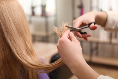 Stylist cutting hair of client in professional salon, closeup