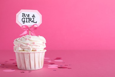 Photo of Beautifully decorated baby shower cupcake with cream and girl topper on pink background. Space for text