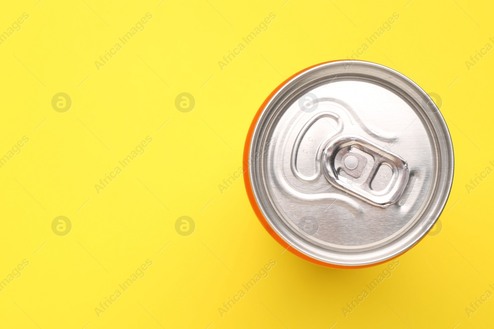 Photo of Energy drink in can on yellow background, top view. Space for text