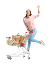 Photo of Young woman with full shopping cart on white background