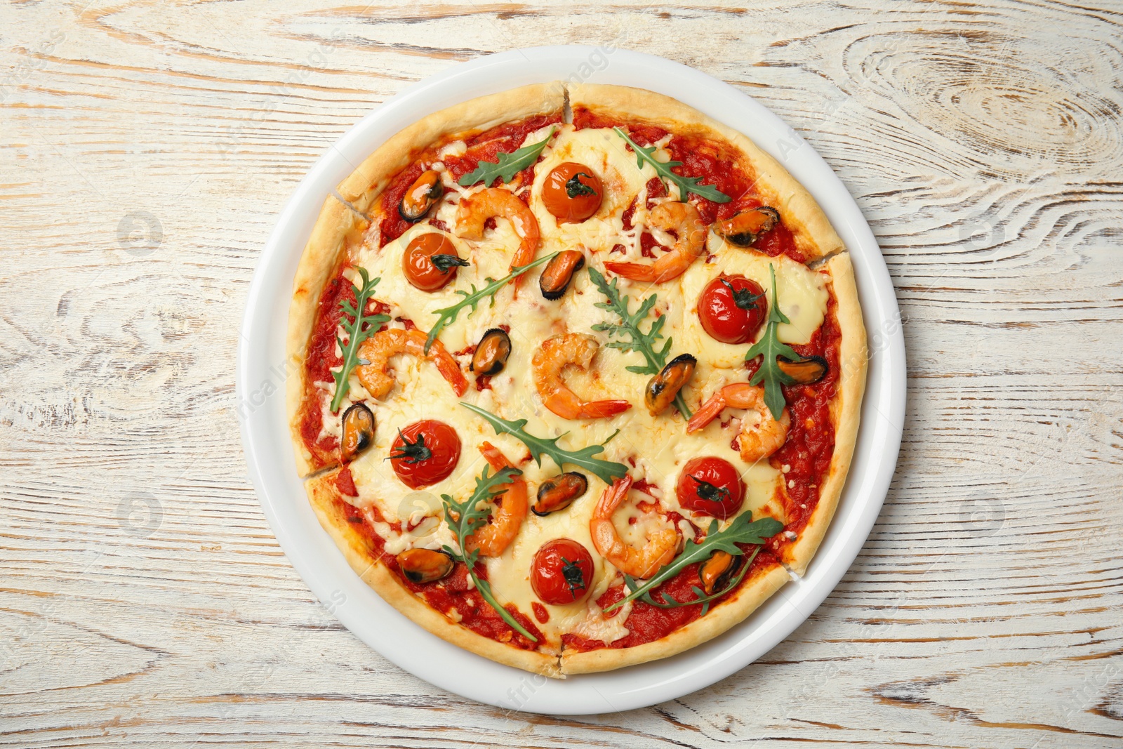 Photo of Delicious seafood pizza on white wooden table, top view