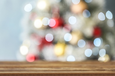 Photo of Empty wooden table and blurred fir tree with Christmas lights on background, bokeh effect. Space for design