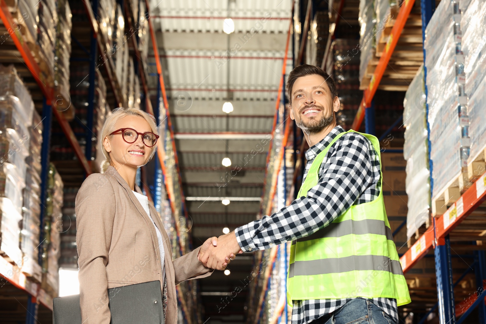 Photo of Happy manager shaking hands with worker in warehouse