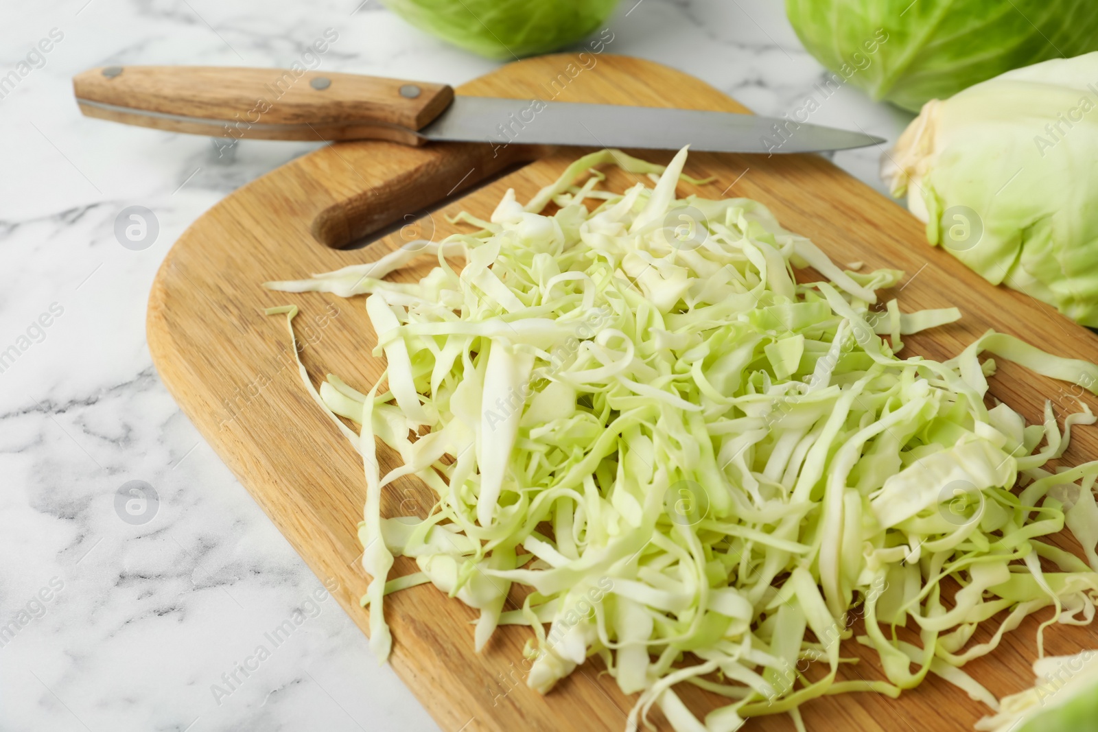 Photo of Chopped ripe cabbage on white marble table, closeup