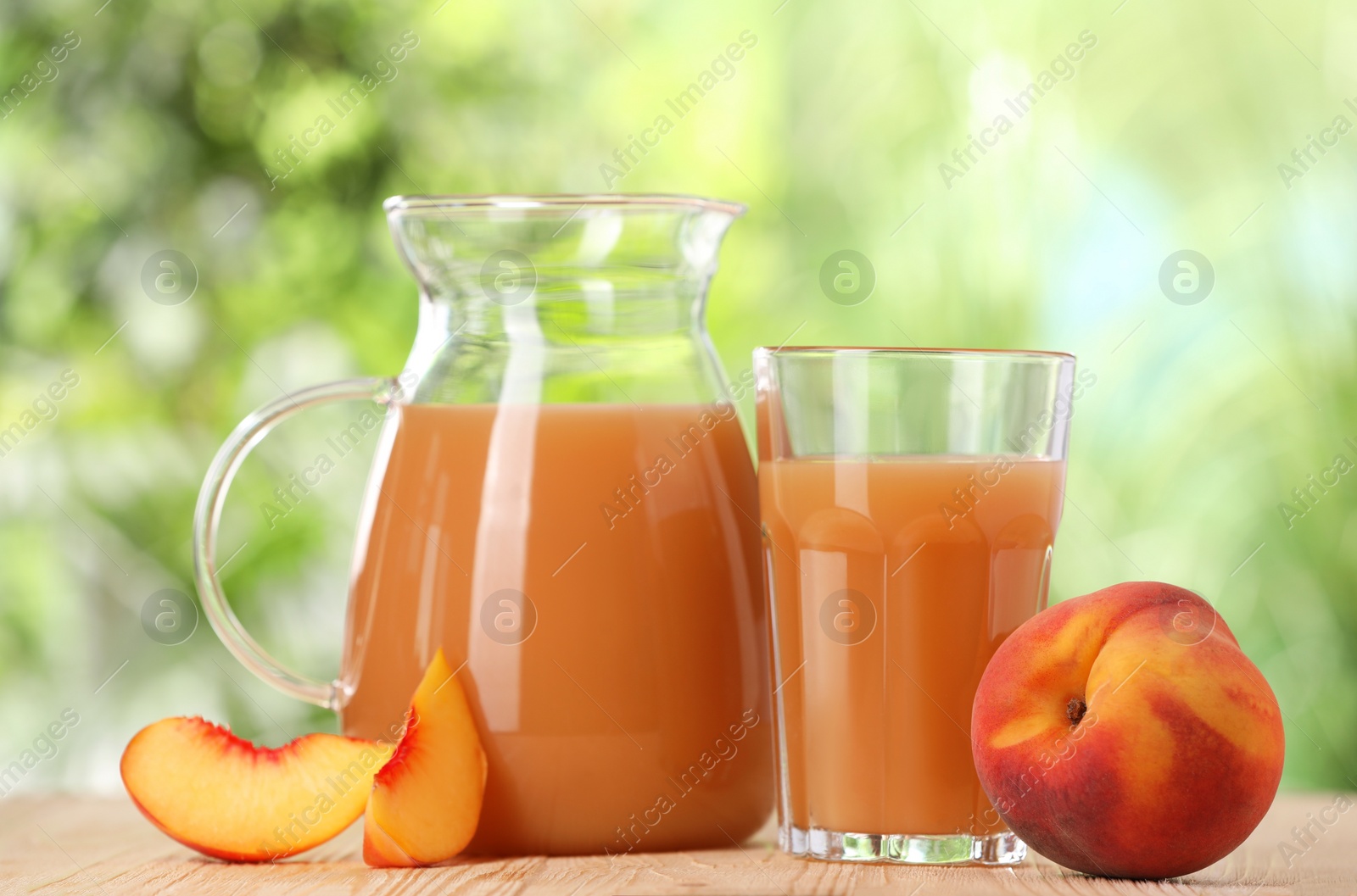 Photo of Tasty peach juice and fresh fruits on wooden table outdoors, closeup