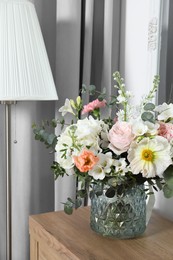 Bouquet with beautiful flowers on wooden chest of drawers indoors