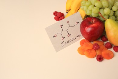 Photo of Card with word Fructose, delicious ripe fruits, raspberries and dried apricots on beige table, space for text