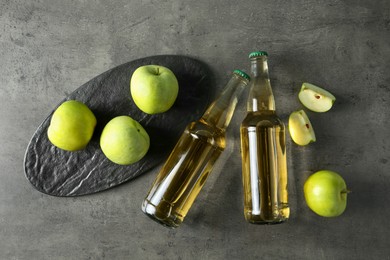 Delicious cider, whole and cut green apples on gray table, flat lay