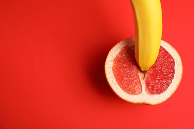 Photo of Flat lay composition with fresh banana and grapefruit on red background. Sex concept