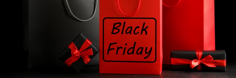 Image of Paper shopping bags and gift boxes on dark background, banner design. Black Friday sale