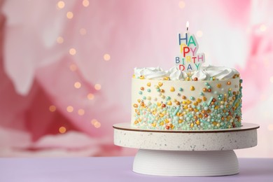Photo of Beautiful birthday cake with burning candle on violet table. Space for text