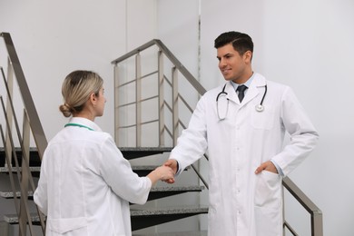 Doctors greeting with handshake on stairs in clinic