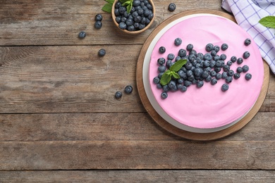 Board with tasty blueberry cake on wooden table, flat lay. Space for text