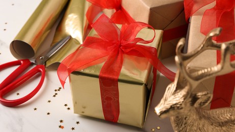 Photo of Beautifully wrapped gift boxes on white table, closeup